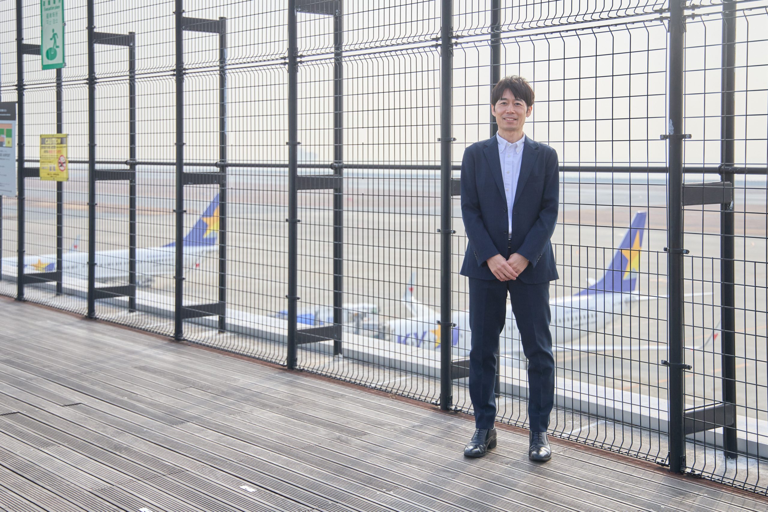 滑走路を背景に立つW.Nさん／Mr W.N. standing against the backdrop of the runway